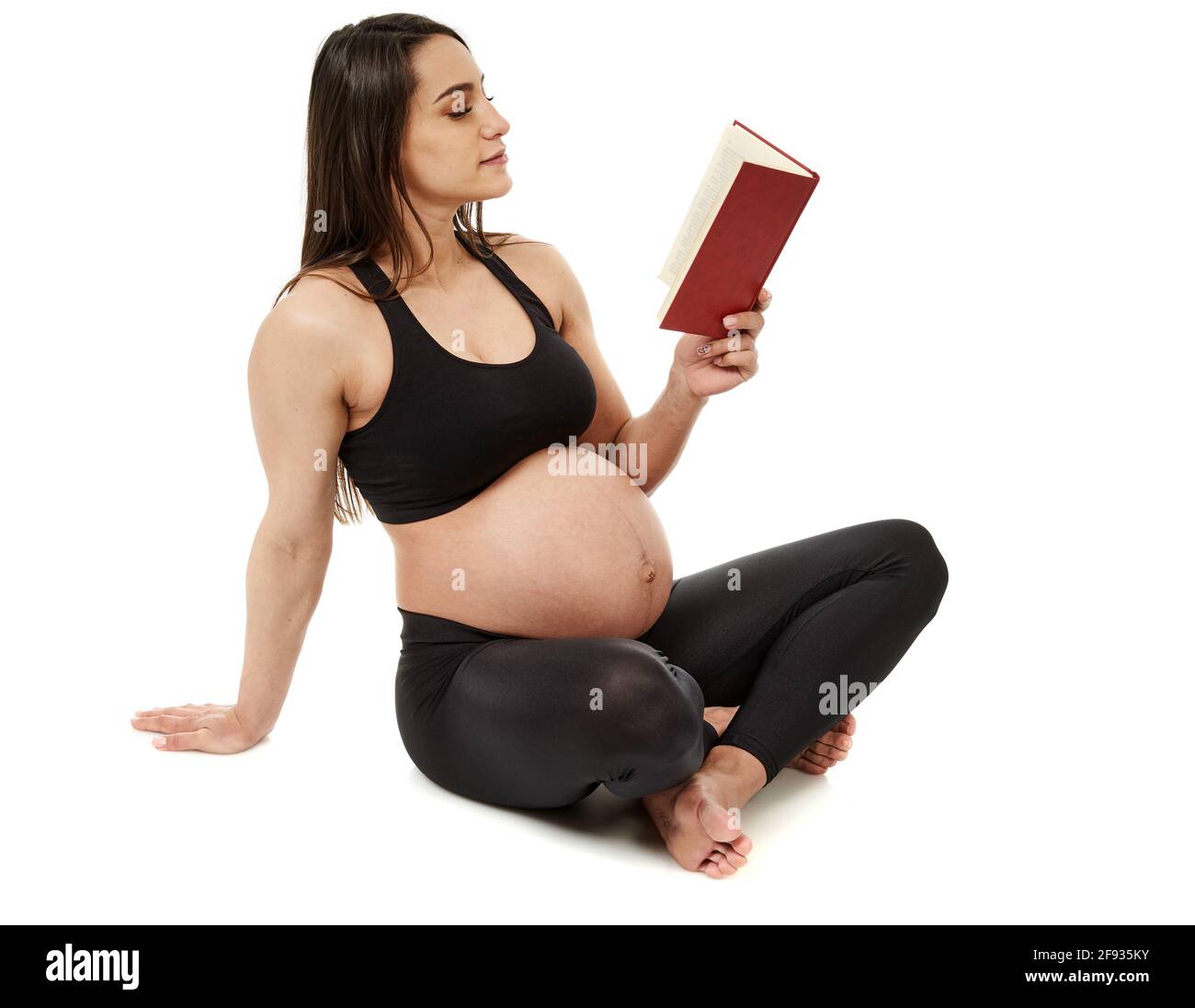 Donna latina incinta che legge libri, isolato su sfondo bianco Foto Stock