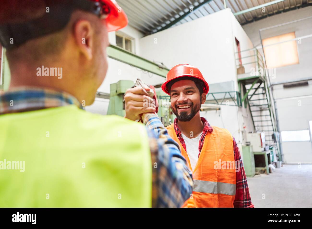 Due artigiani o lavoratori si salutano con un compagno stretta di mano in fabbrica Foto Stock