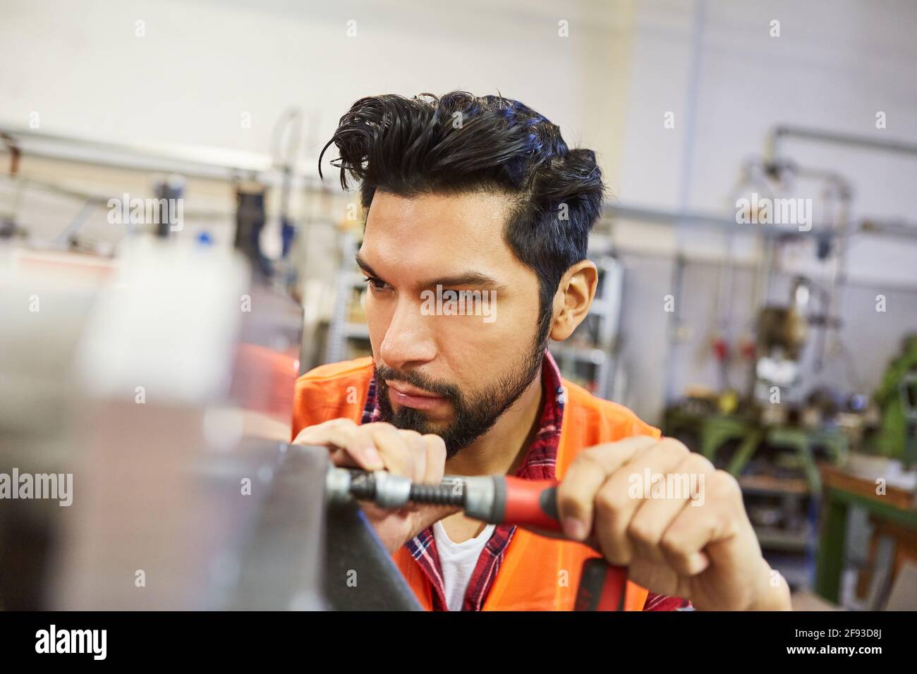 L'uomo in fabbro o l'addestramento del lavoratore del metallo lavora in metallo officina di costruzione Foto Stock