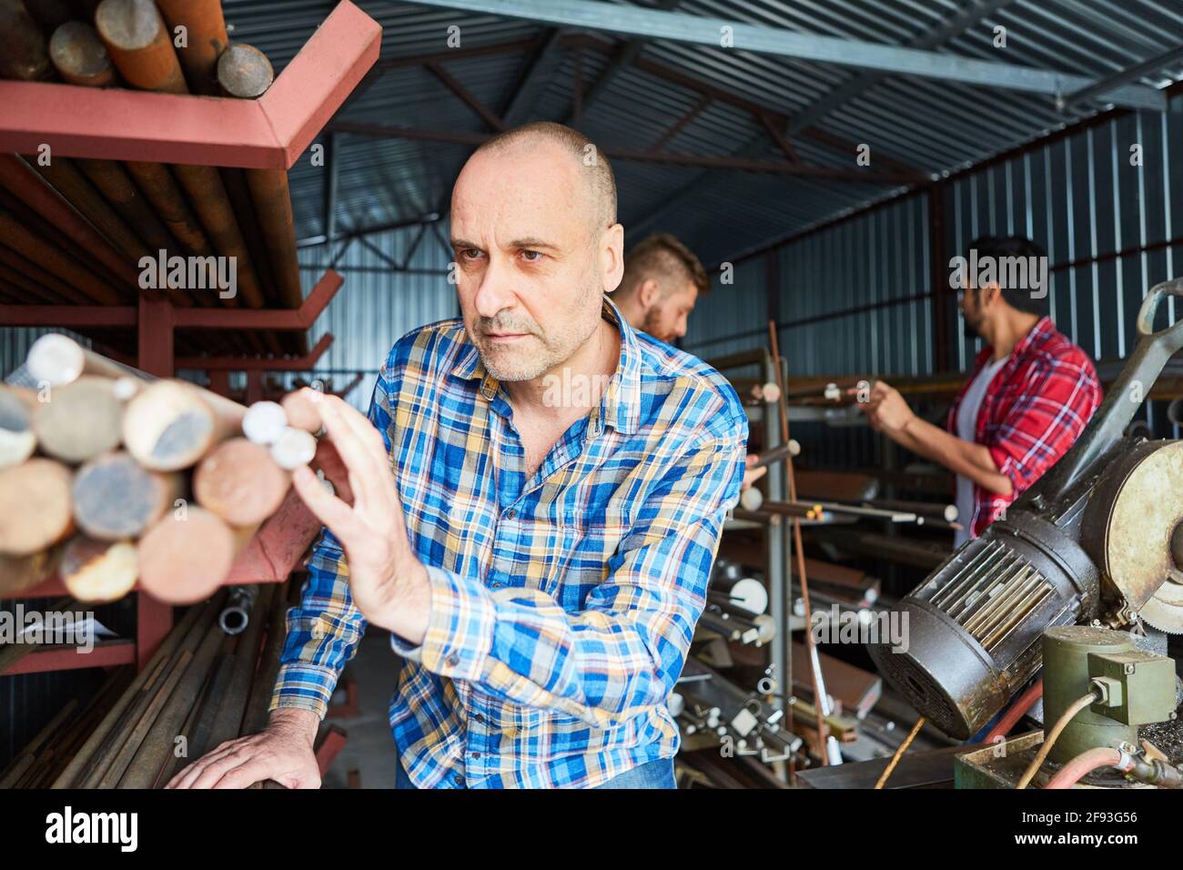 Metal worker come addetto al magazzino durante il controllo dell'inventario in magazzino dei materiali della bottega del fabbro Foto Stock