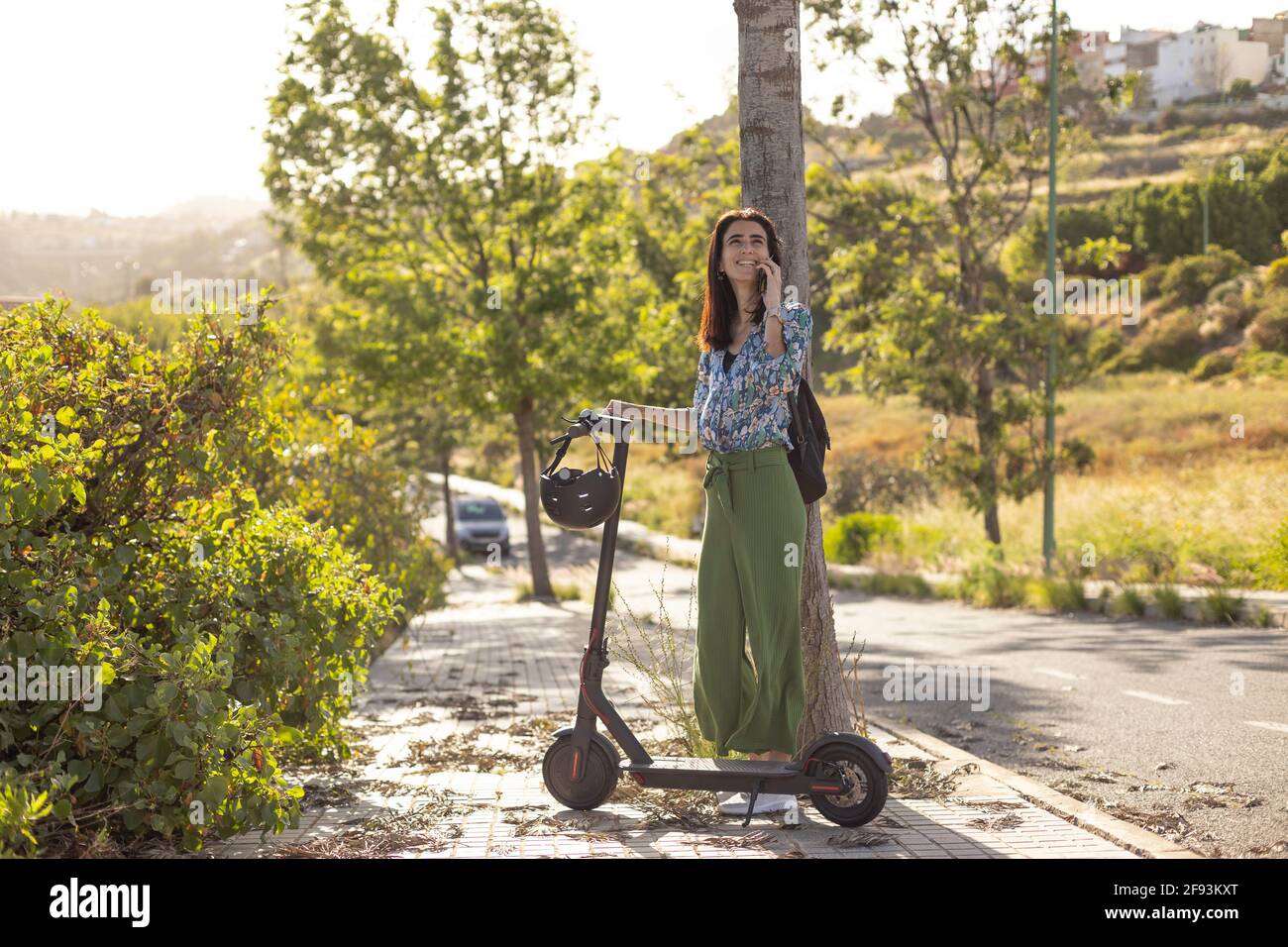 Donna su scooter elettrico parla su smartphone Foto Stock