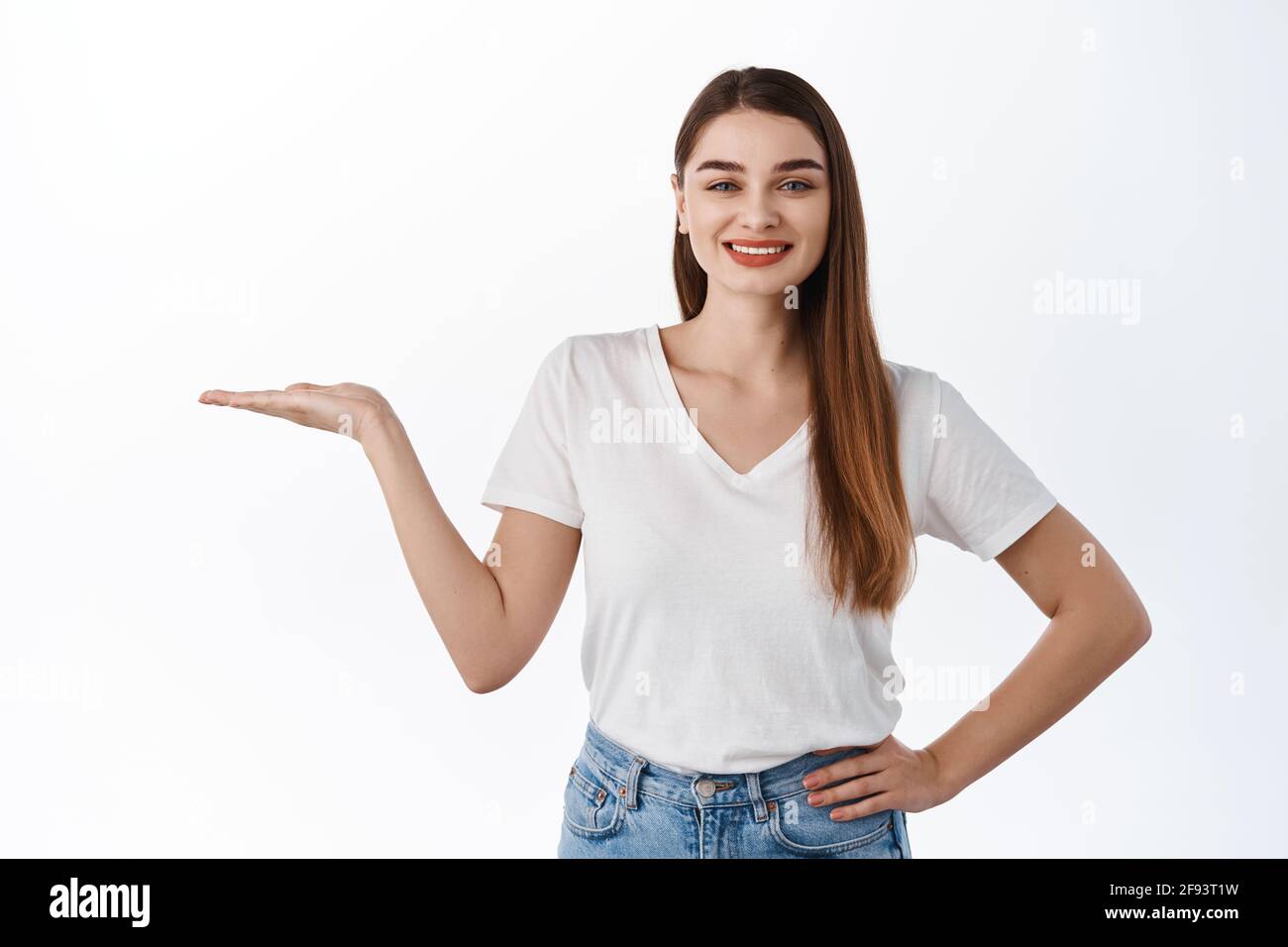 Sorridente ragazza sana allungare la mano aperta e tenendo il vostro logo, prodotto promozionale, visualizzare un articolo sullo spazio di copia, raccomandando acquistare articolo, in piedi Foto Stock