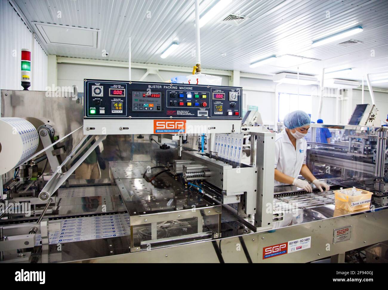 Atyrau, Kazakistan. Impianto di produzione siringhe mediche. Giovane operatore donna Asain sulla linea di produzione Foto Stock
