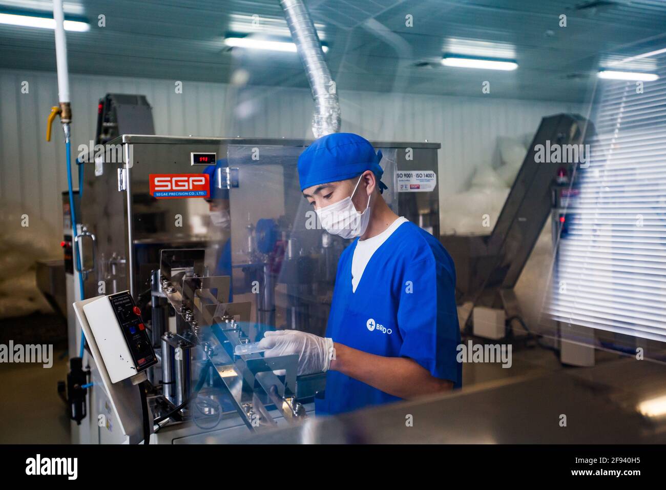 Atyrau, Kazakistan. Impianto di produzione di siringhe mediche. Giovane operatore asiatico sulla linea di produzione. Foto Stock