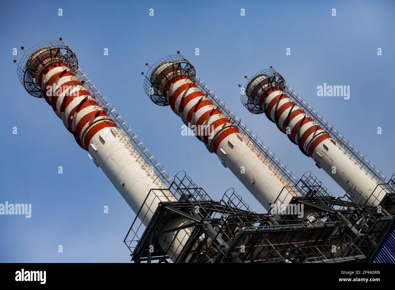 Pile di fumo rosse e bianche a strisce (camini di piante) su sfondo blu del cielo. Moderna centrale a gas. Primo piano. Vista diagonale. Foto Stock