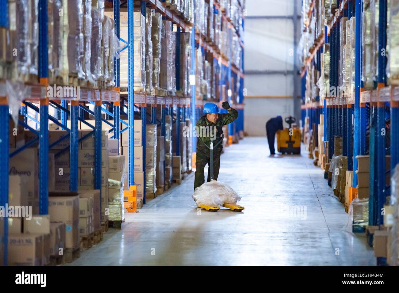 Moderno centro logistico e magazzino. Operatore con carrello manuale. Aktobe, Kazakistan. Foto Stock