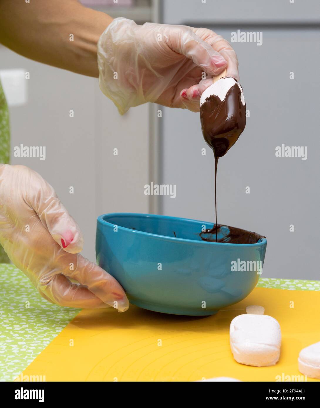 Marshmallows su un bastone immerso nel cioccolato. Il processo di smaltatura. Messa a fuoco selettiva. Foto Stock