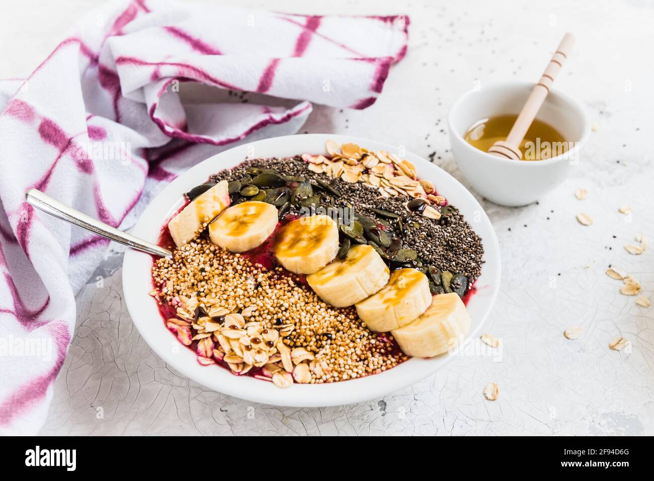 Colazione sana. Recipiente per frullato con mirtilli, banana, fiocchi di avena, semi di chia, quinoa, semi di zucca e miele. Foto Stock