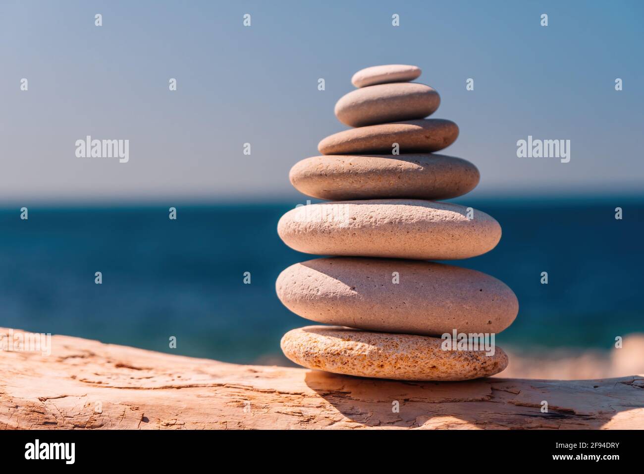 Equilibrata piramide di ciottoli sulla spiaggia in una giornata di sole. Abstract Sea bokeh sullo sfondo. Messa a fuoco selettiva. Pietre Zen sulla spiaggia di mare, meditazione Foto Stock