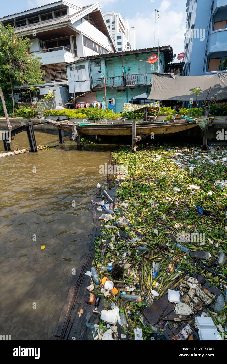 La superficie del fiume è inquinata da rifiuti e plastica miscelati con piante d'acqua tropicali locali in un estury nell'area urbana di Bangkok, Thailandia. Foto Stock