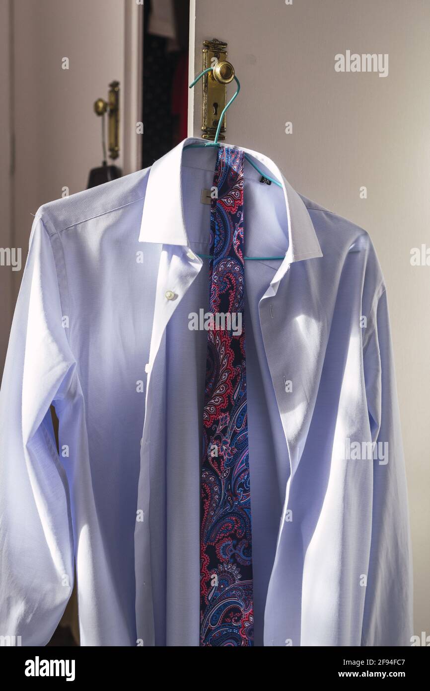 Immagine verticale di una camicia blu con cravatta appesa una maniglia  della porta Foto stock - Alamy