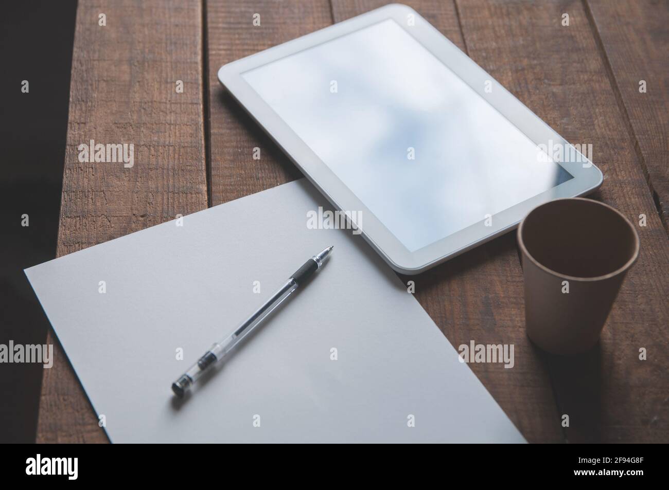 Ambiente di lavoro in ufficio con tablet pc sul tavolo. Sul tavolo c'è una compressa e un foglio bianco di carta con una penna. Per una presentazione o un portf di disegno Foto Stock