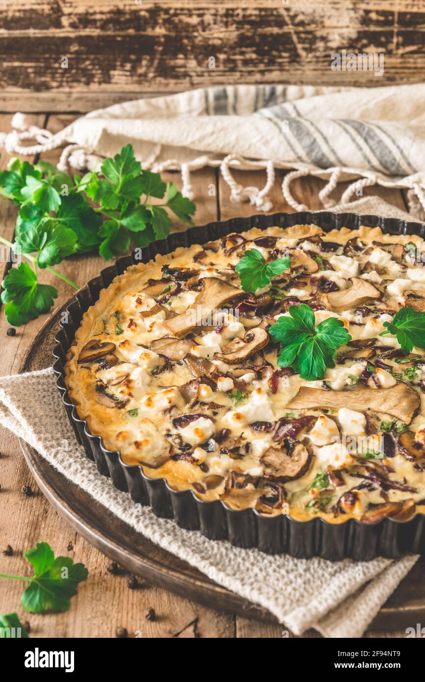 Quiche di funghi vegetariani con prezzemolo su tavola di legno, verticale Foto Stock
