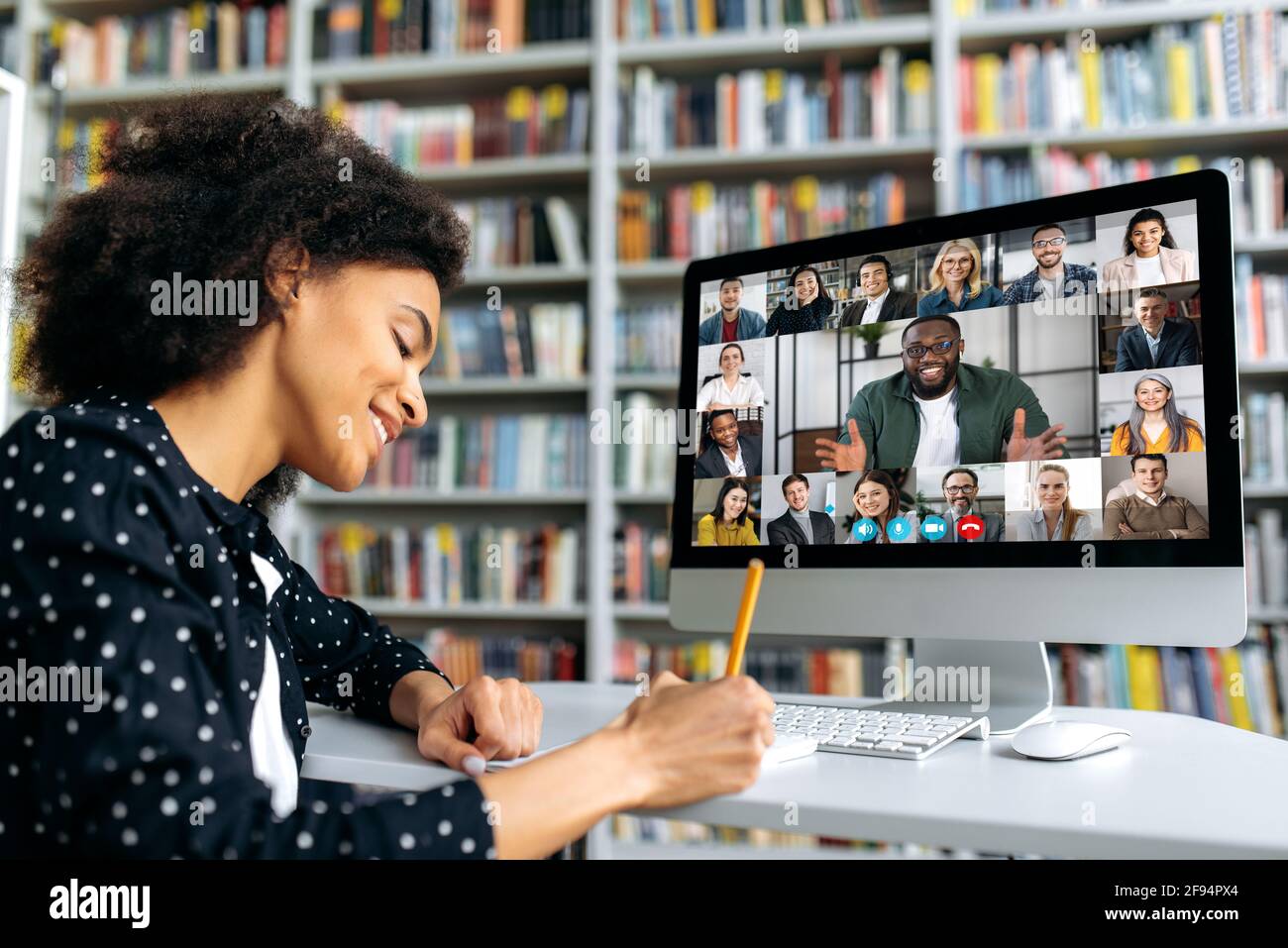 Videochiamata, formazione online. Afroamericana studentessa felice, imparando a distanza, guarda una lezione online, prendendo appunti, gente sorridente multirazziale su uno schermo del computer, comunicazione virtuale Foto Stock