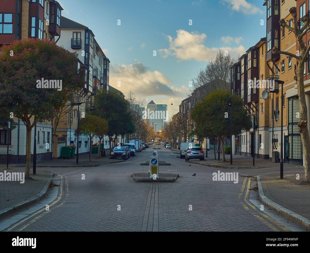 Londra UK Dic 2019- una strada residenziale, case, automobili e alberi, che guarda attraverso un arenato Canary Wharf, che sorge come un miraggio all'orizzonte Foto Stock