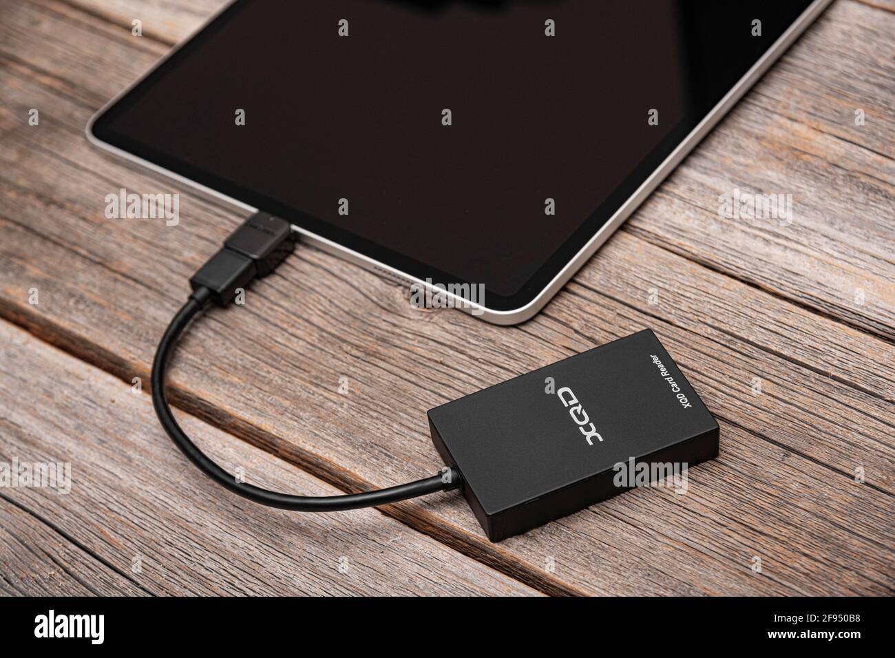 Un iPad Pro Apple con una scheda di memoria XQD collegata tramite OTG tramite un lettore di schede. Foto Stock