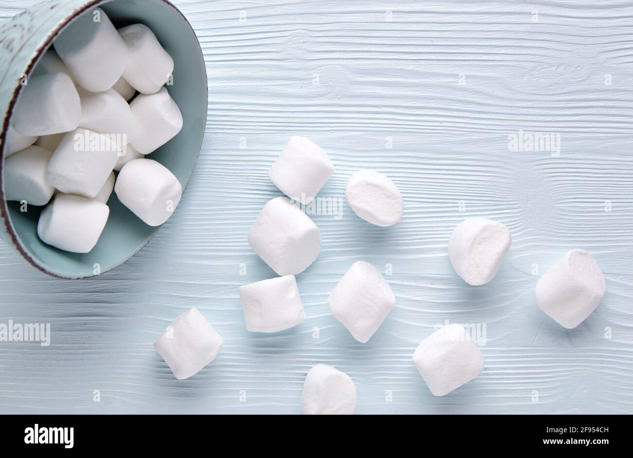 Marshmallow bianco in una tazza su uno sfondo di legno chiaro. Foto Stock