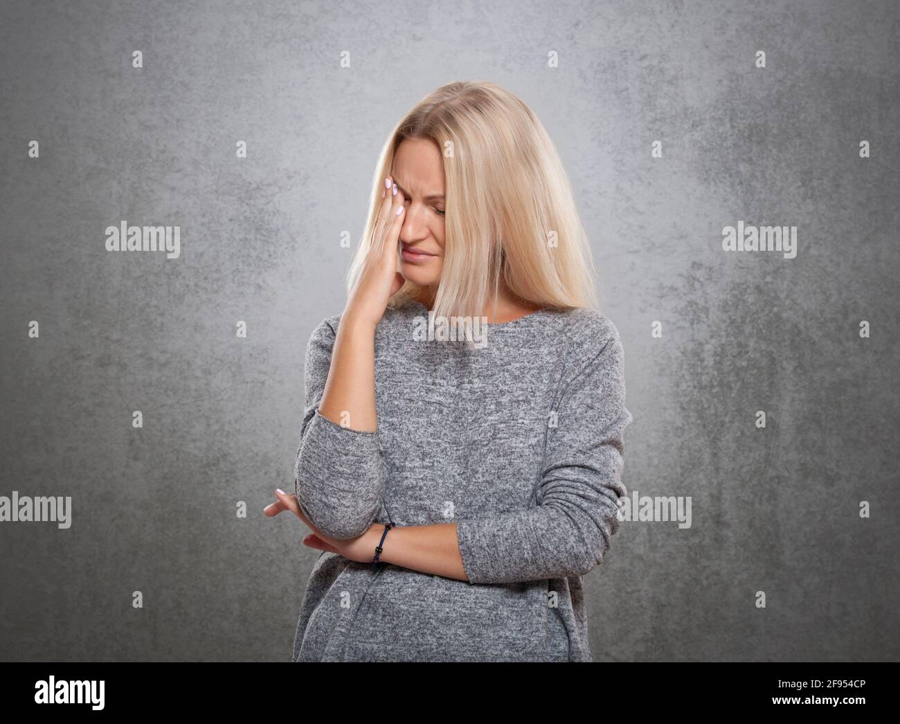 Donne con un volto triste. Su un fondo grigio concreto., donne con un volto triste. Su uno sfondo grigio di cemento. Foto Stock