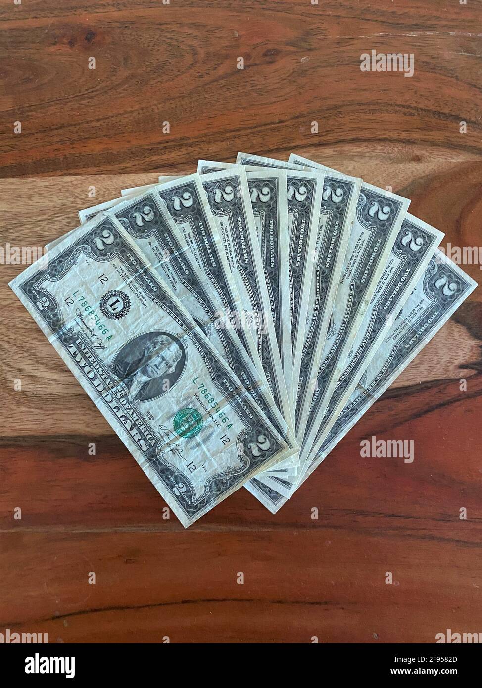 Fan di due dollari bollette isolato su uno sfondo di legno. Foto Stock