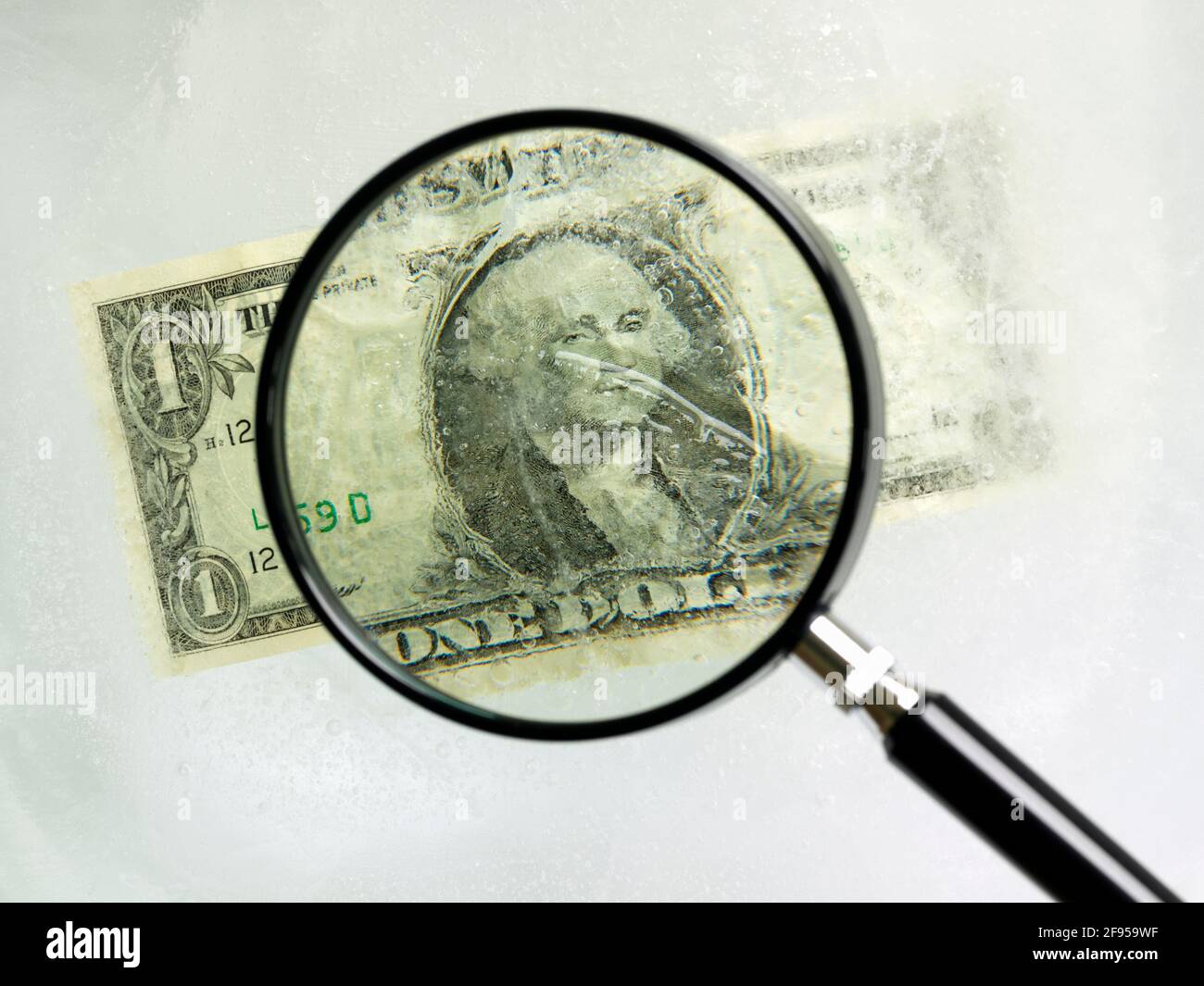 Il conto del dollaro americano racchiuso nel ghiaccio visto attraverso un ingrandimento vetro Foto Stock