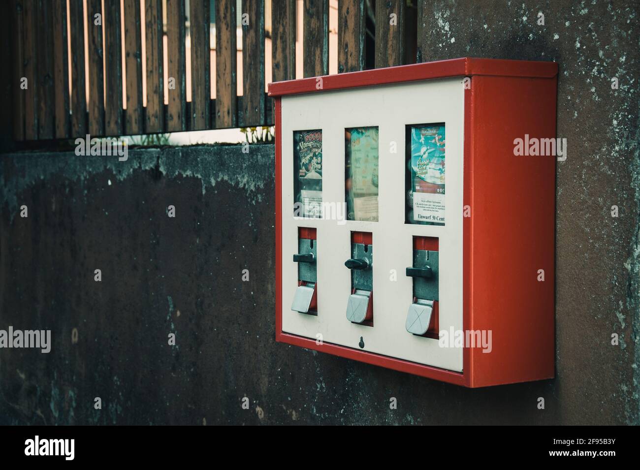 Distributore automatico di gomme da masticare appeso su una parete ruvida Foto Stock