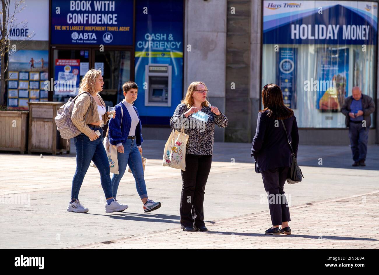 Dundee, Tayside, Scozia, Regno Unito. 16 Apr 2021. Regno Unito tempo: Una giornata di sole fresco in tutto il Nord-Est della Scozia con temperature che raggiungono i 14°C. Il blocco Covid-19 si sta allentando con la gente che fa shopping e socializza nel centro della città di Dundee con alcuni negozi essenziali aperti per affari nella strada alta. Gli acquirenti fuori dall'agenzia di viaggi Hay`s approfittano delle nuove e rilassanti norme di blocco e delle soleggiate condizioni meteorologiche di aprile per incontrarsi per una chiacchierata durante una giornata di shopping. Credit: Dundee Photographics/Alamy Live News Foto Stock