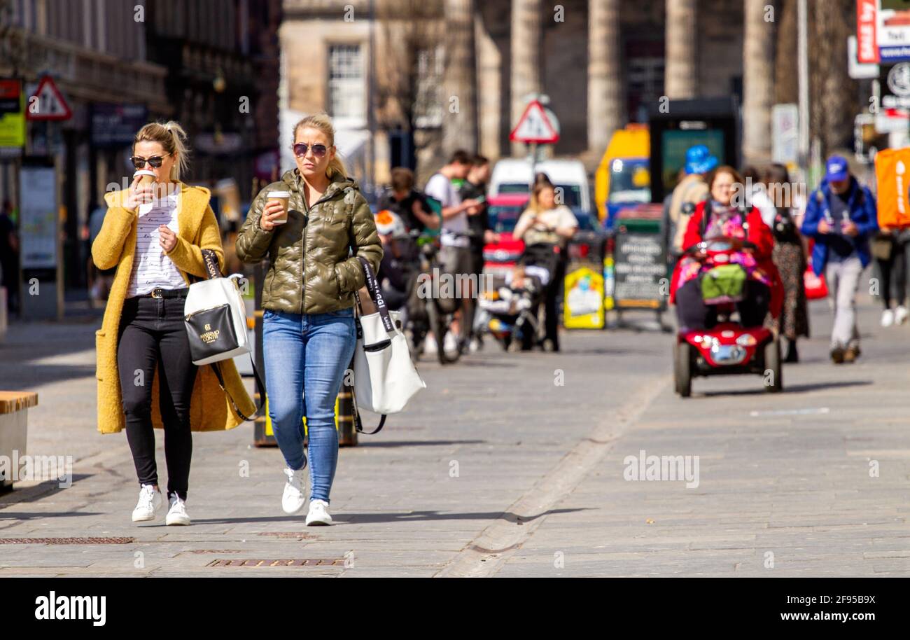 Dundee, Tayside, Scozia, Regno Unito. 16 Apr 2021. Regno Unito tempo: Una giornata di sole fresco in tutto il Nord-Est della Scozia con temperature che raggiungono i 14°C. Il blocco Covid-19 si sta allentando con la gente che fa shopping e socializza nel centro della città di Dundee con alcuni negozi essenziali aperti per affari nella strada alta. Due donne alla moda approfittano delle nuove e rilassanti regole di blocco e del clima soleggiato di aprile per camminare insieme bevendo caffè durante una giornata di shopping. Credit: Dundee Photographics/Alamy Live News Foto Stock