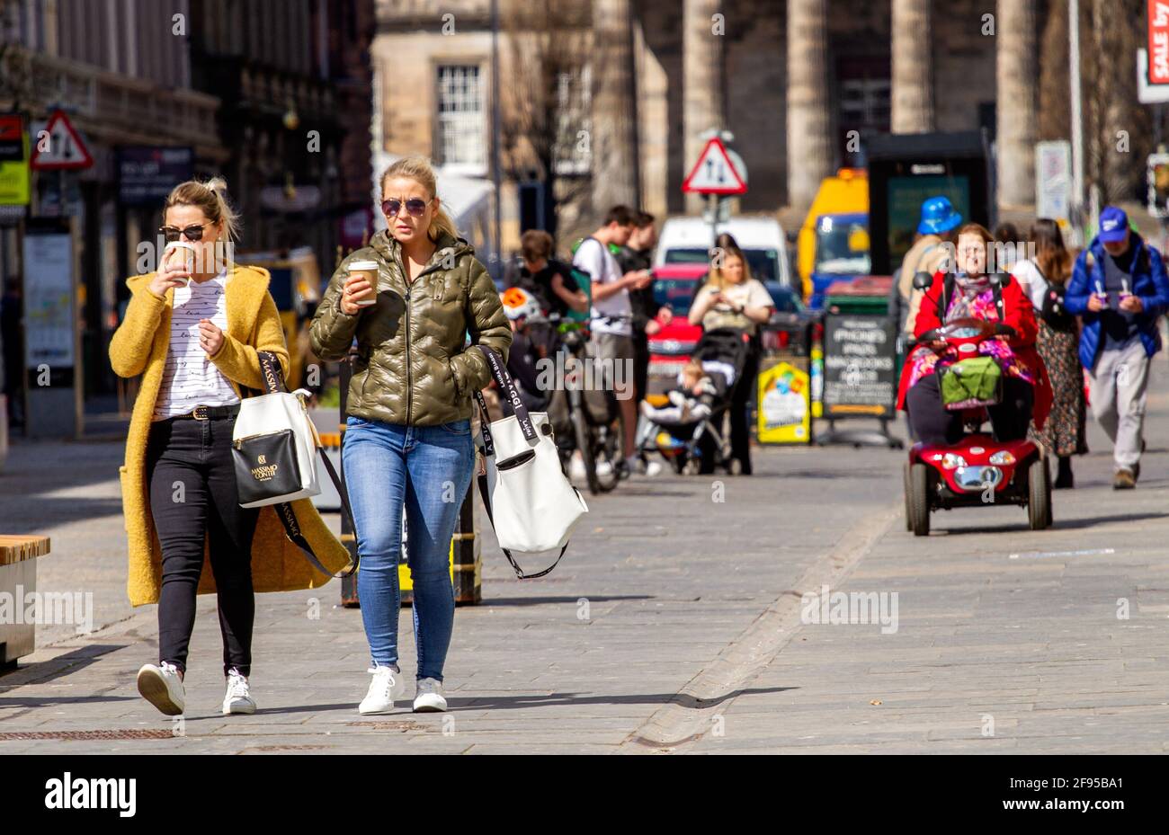 Dundee, Tayside, Scozia, Regno Unito. 16 Apr 2021. Regno Unito tempo: Una giornata di sole fresco in tutto il Nord-Est della Scozia con temperature che raggiungono i 14°C. Il blocco Covid-19 si sta allentando con la gente che fa shopping e socializza nel centro della città di Dundee con alcuni negozi essenziali aperti per affari nella strada alta. Due donne alla moda approfittano delle nuove e rilassanti regole di blocco e del clima soleggiato di aprile per camminare insieme bevendo caffè durante una giornata di shopping. Credit: Dundee Photographics/Alamy Live News Foto Stock