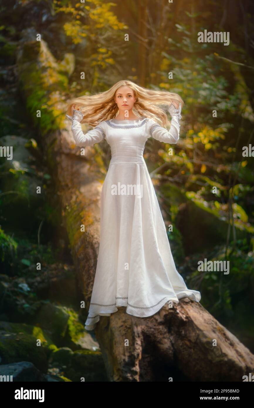 Bella giovane donna in un vestito bianco al centro di una foresta Foto Stock