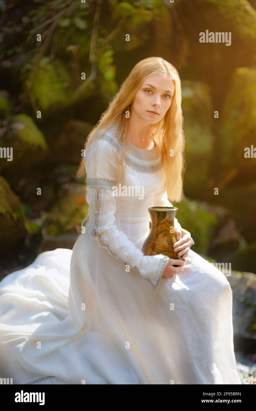 Bella giovane donna in un vestito bianco al centro di una foresta Foto Stock