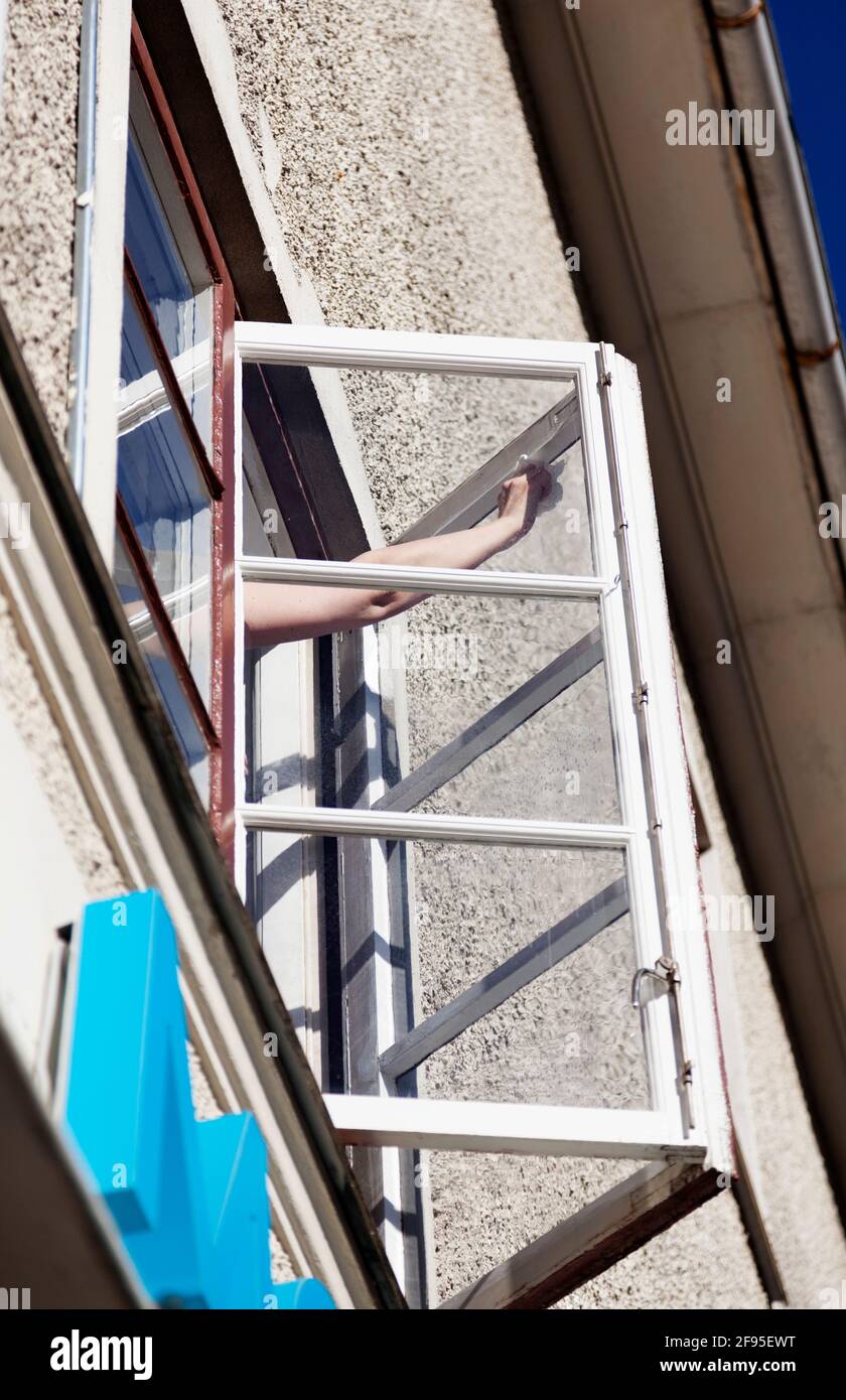Umea, Norrland Svezia - 17 marzo 2021: La mano di una donna pulisce le finestre al secondo piano Foto Stock
