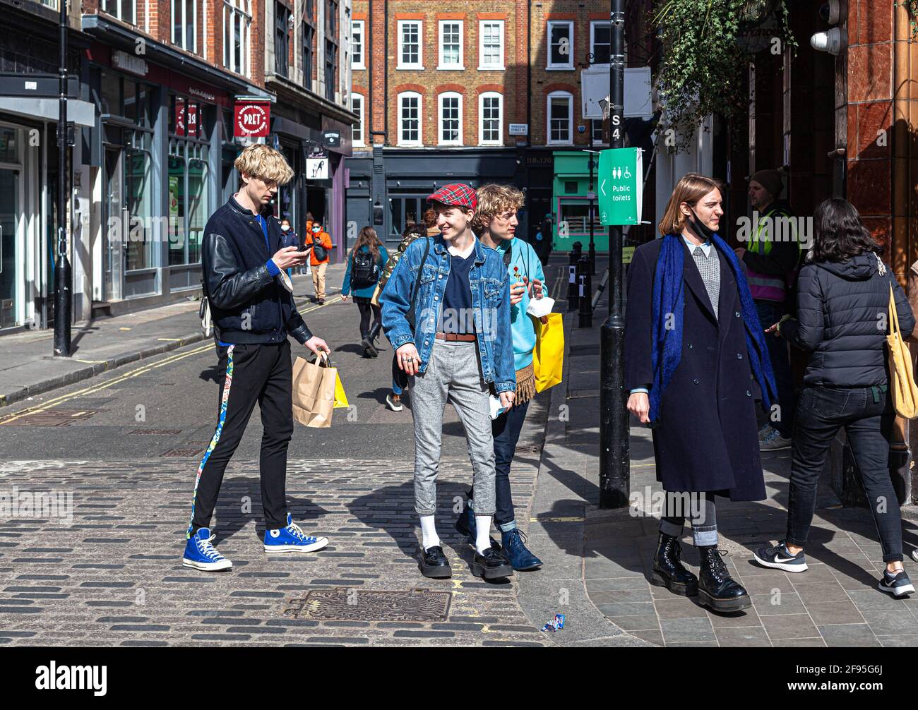 Un gruppo di giovani uomini alla moda che camminano su una strada, Soho, Londra, Inghilterra, Regno Unito. Foto Stock