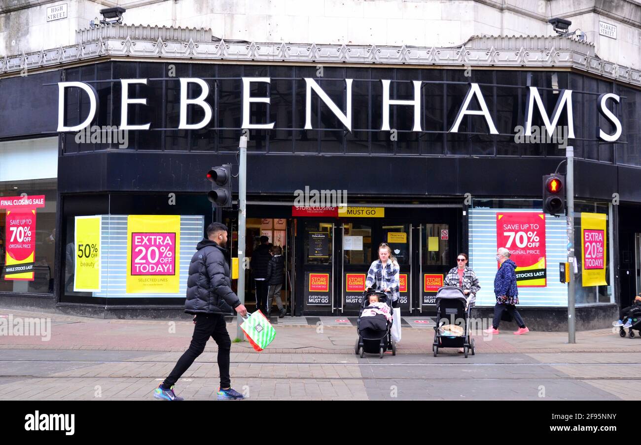La gente passa davanti a un negozio Debenhams a Manchester, Greater Manchester, Inghilterra, Regno Unito, che mostra poster "vendita di chiusura". Debenhams ha riaperto dozzine dei suoi negozi nel mese di aprile 2021 per una chiusura della vendita per la liquidazione delle scorte prima di una chiusura finale il 15 maggio. Il grande magazzino, crollato nel 2020, offre fino al 70% di sconto sulle sue scorte. Il Covid 19 o Coronavirus lockdown ha colpito mattoni e mortaio negozi duro. Foto Stock