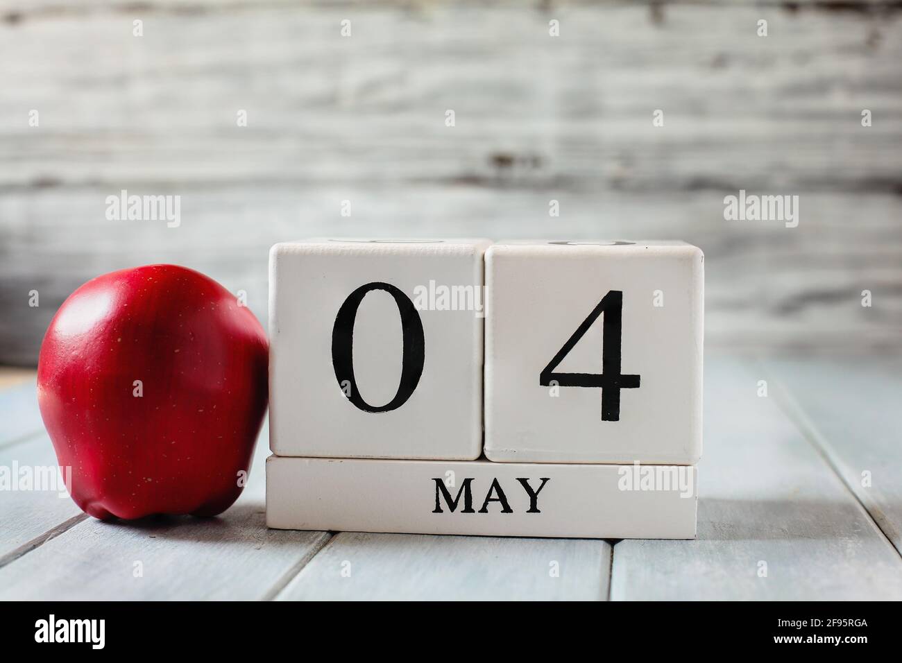 Il calendario in legno bianco si blocca con la data del 4 maggio e una mela rossa per il National Teacher Appreciation Day. Foto Stock