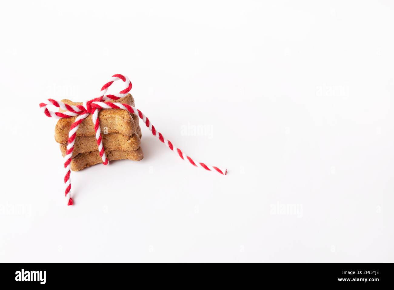 Piccola pila di tre biscotti marroni del cane legati in rosso e una stringa bianca Foto Stock
