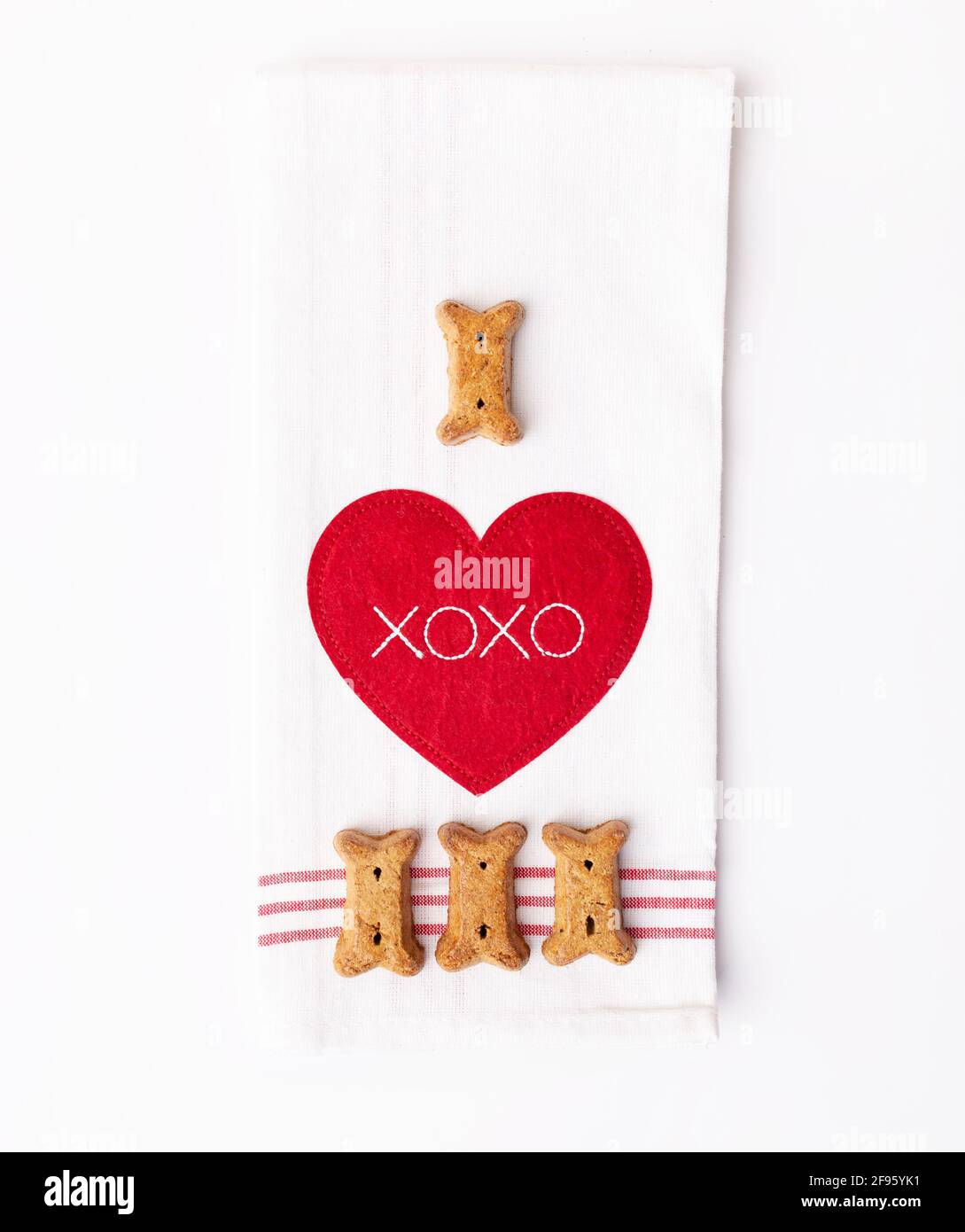 Quattro ossee a forma di cane treats su piatto rosso e bianco asciugamano con cuore Foto Stock