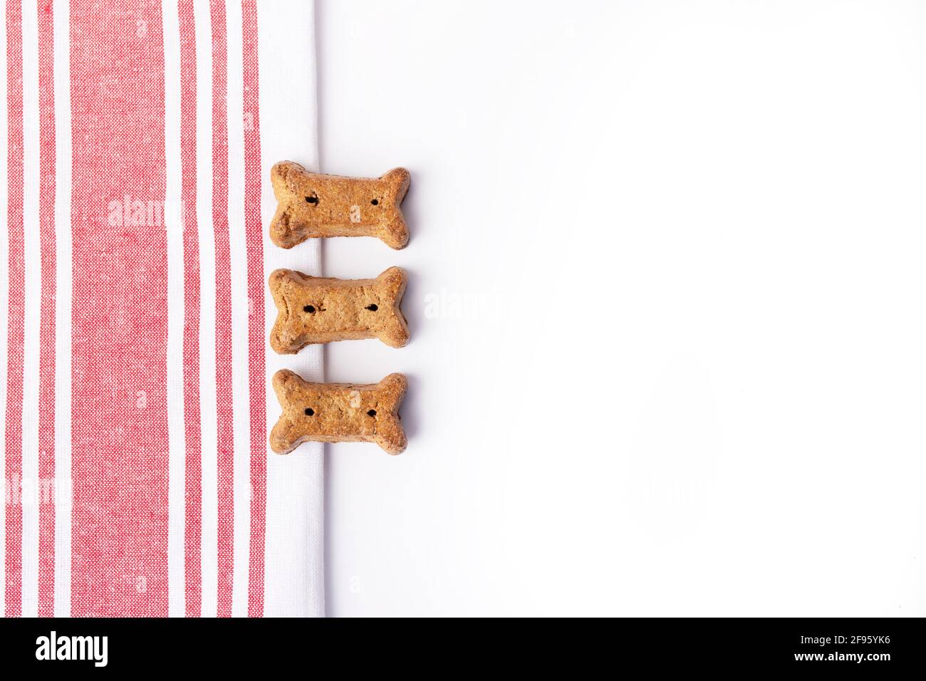Tre ossee a forma di cane treats su strisce rosse e bianche asciugamano bianco Foto Stock
