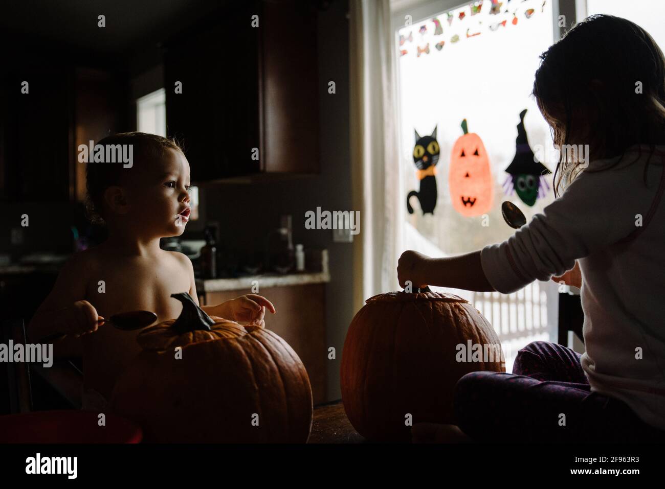 Due bambini che intagliano la zucca ad Halloween a casa loro Foto Stock