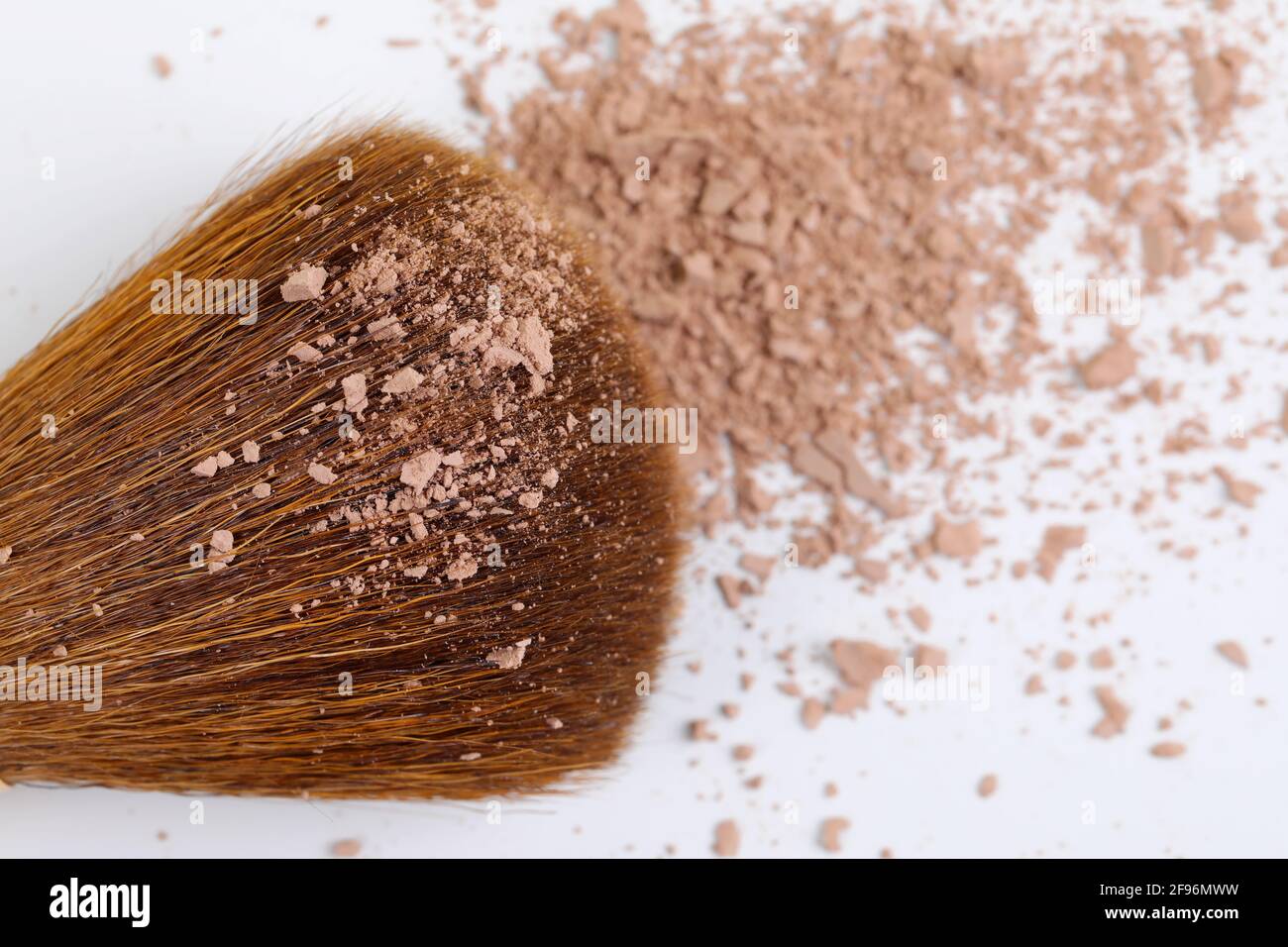 Polvere sfoltata e spazzola di trucco del viso di colore marrone scuro, isolata su sfondo bianco. Spazio di copia. Disposizione piatta. Foto Stock