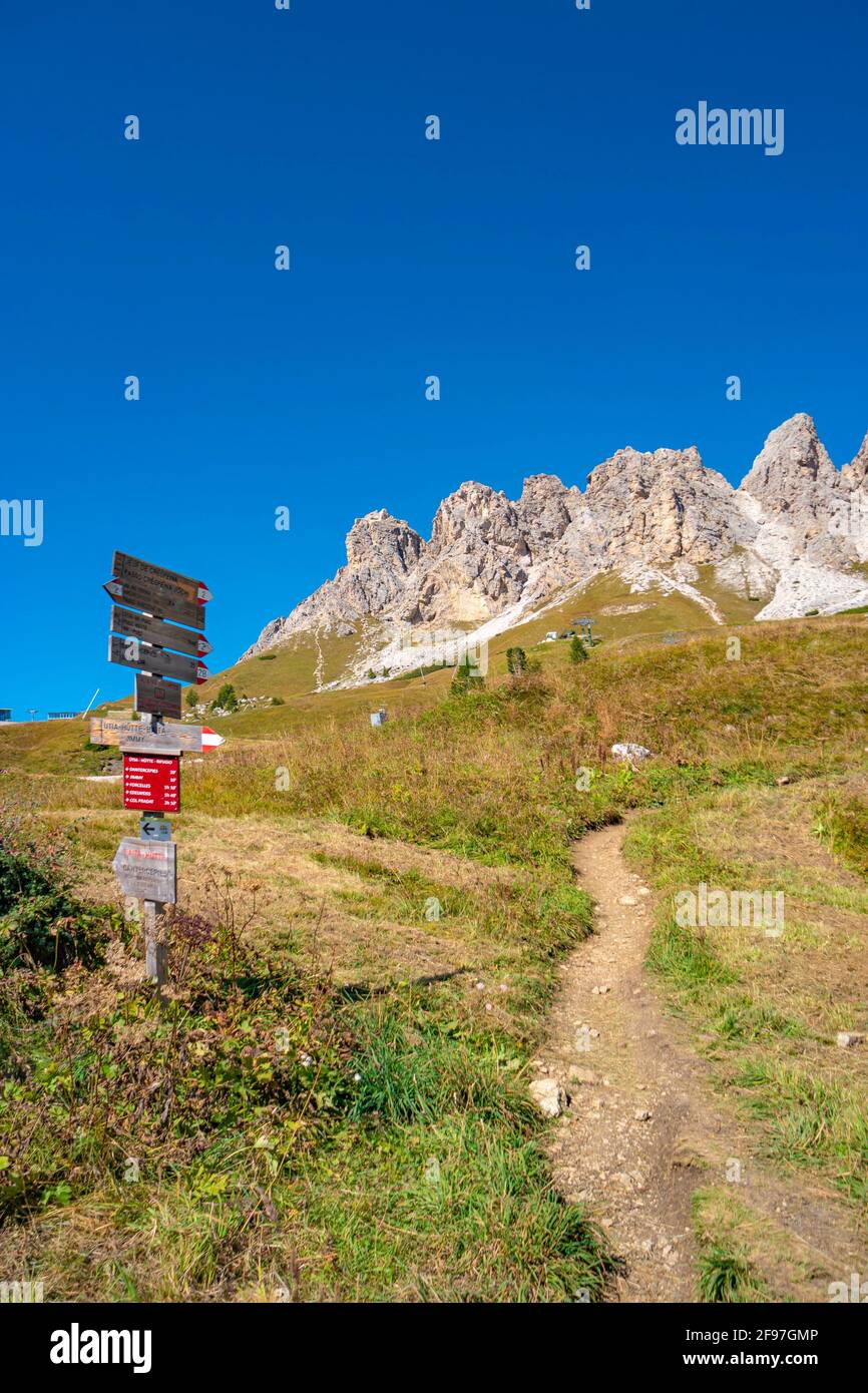 Magiche vette dolomitiche di Pizes da Cir, Passo Gardena al cielo azzurro e giornata di sole con un cartello con la direzione di un sentiero escursionistico, Alto Adige, Italia Foto Stock