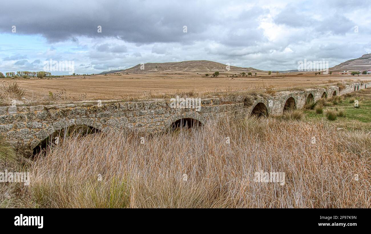 Fiume asciutto con erba alta e un ponte romano attraverso la pianura spagnola Meseta a Castrojeriz, 21 ottobre 2009 Foto Stock