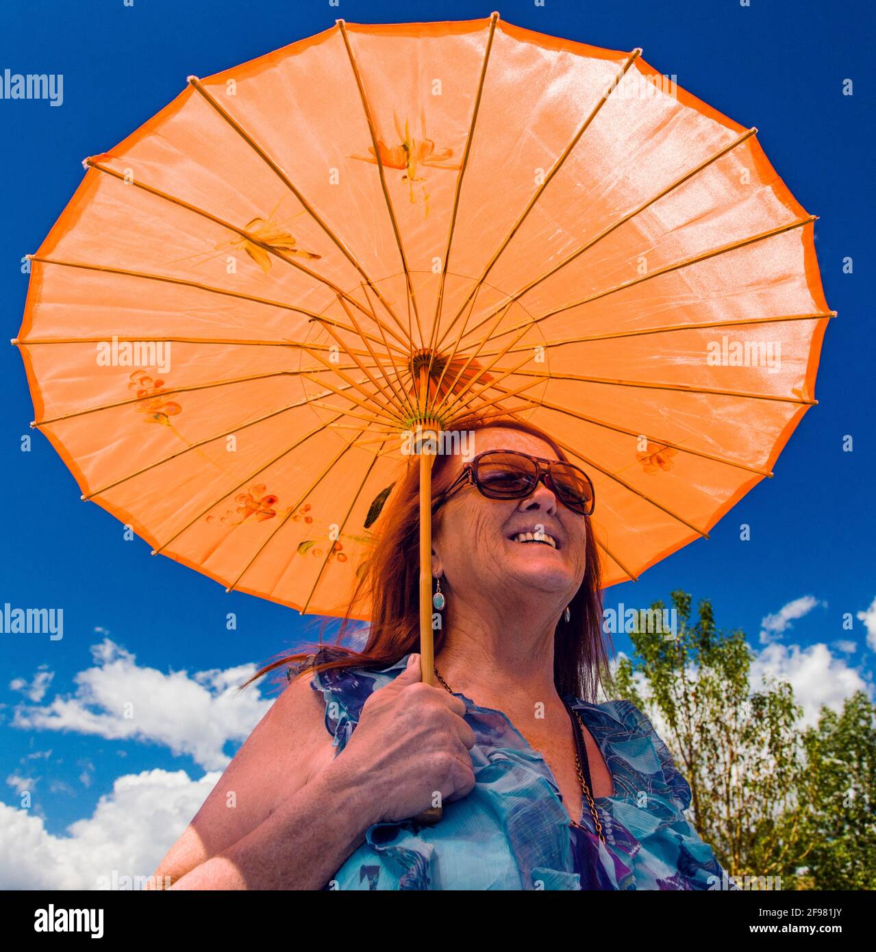 Outdoor ritratto di donna con un arancione ombrellone, piccolo paese di montagna di Buena Vista, Colorado, STATI UNITI D'AMERICA Foto Stock
