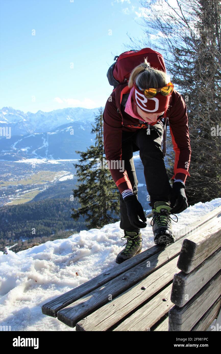 La donna lega le sue lacci durante l'escursione invernale a Schafkopf vicino a Farchant, Europa, Germania, Baviera, alta Baviera, Garmisch-Partenkirchen, Loisachtal, Foto Stock