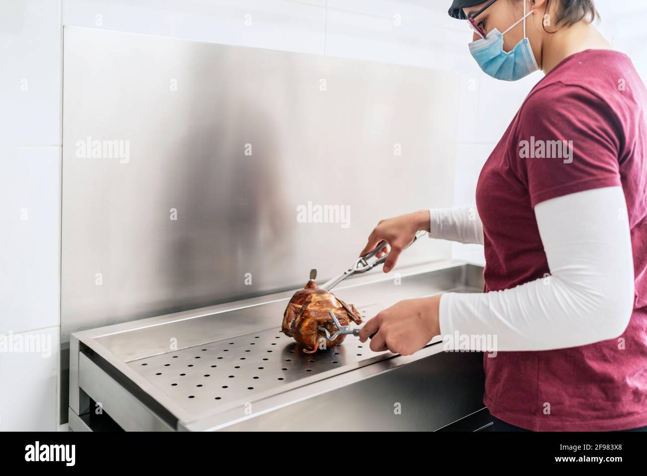 cuoco femminile tagliando un pollo dopo averlo cucinato Foto Stock