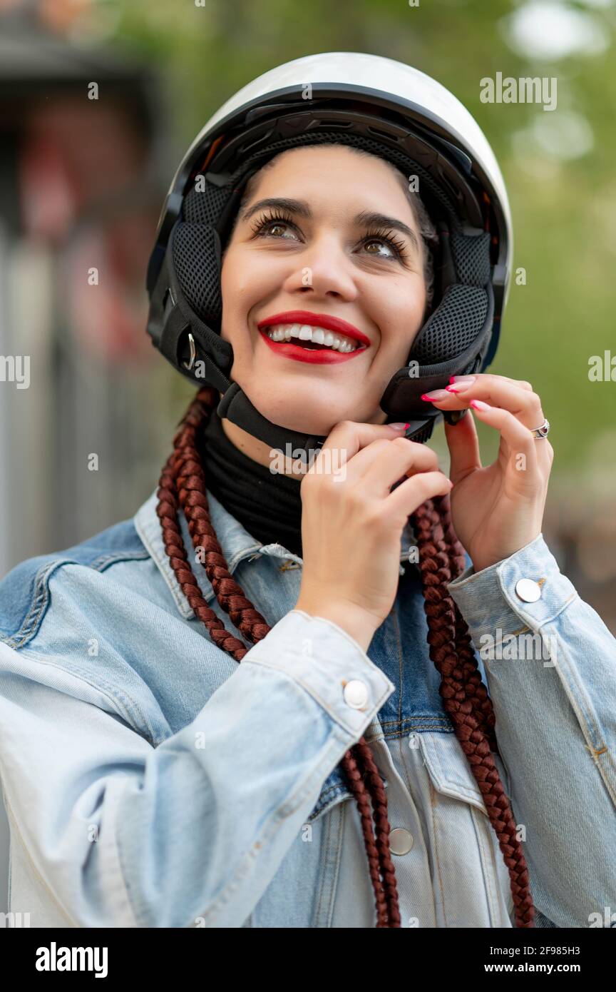 Primo piano di una giovane donna che fissa un casco protettivo per motociclette Foto Stock