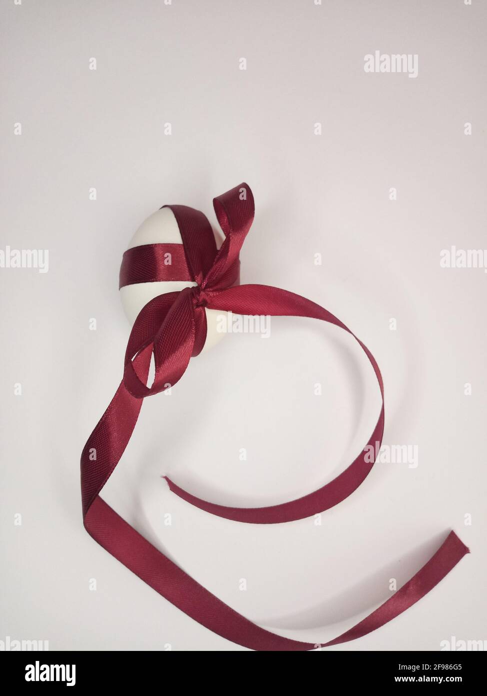 Uovo decorato con un nastro di borgogna con un arco Foto Stock