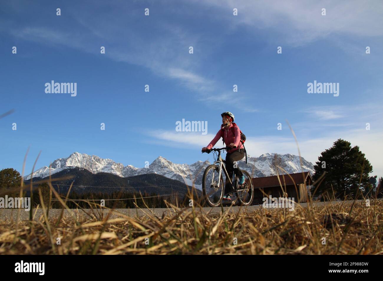 Tour in bicicletta con una mountain bike nei pascoli di Mittenwald, Germania, Baviera, alta Baviera, Valle d'Isar, Strada, sentiero, casco da bicicletta, bicicletta, Monti Karwendel, cielo blu Foto Stock