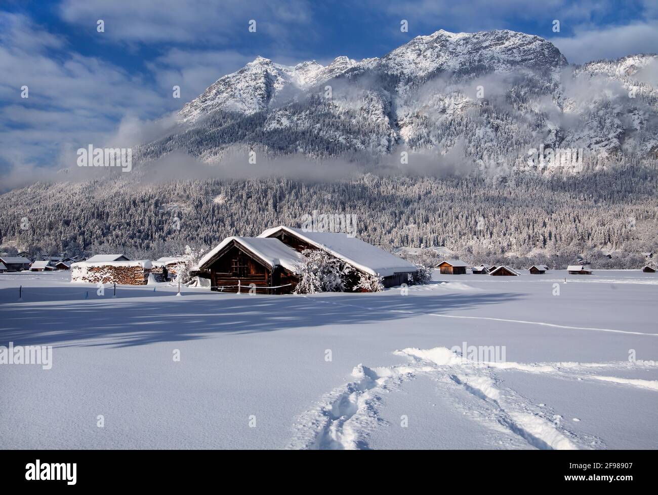 Paesaggio invernale con fienili contro Kramerspitz (1985 m), Garmisch-Partenkirchen, Werdenfelser Land, alta Baviera, Baviera, Germania Foto Stock