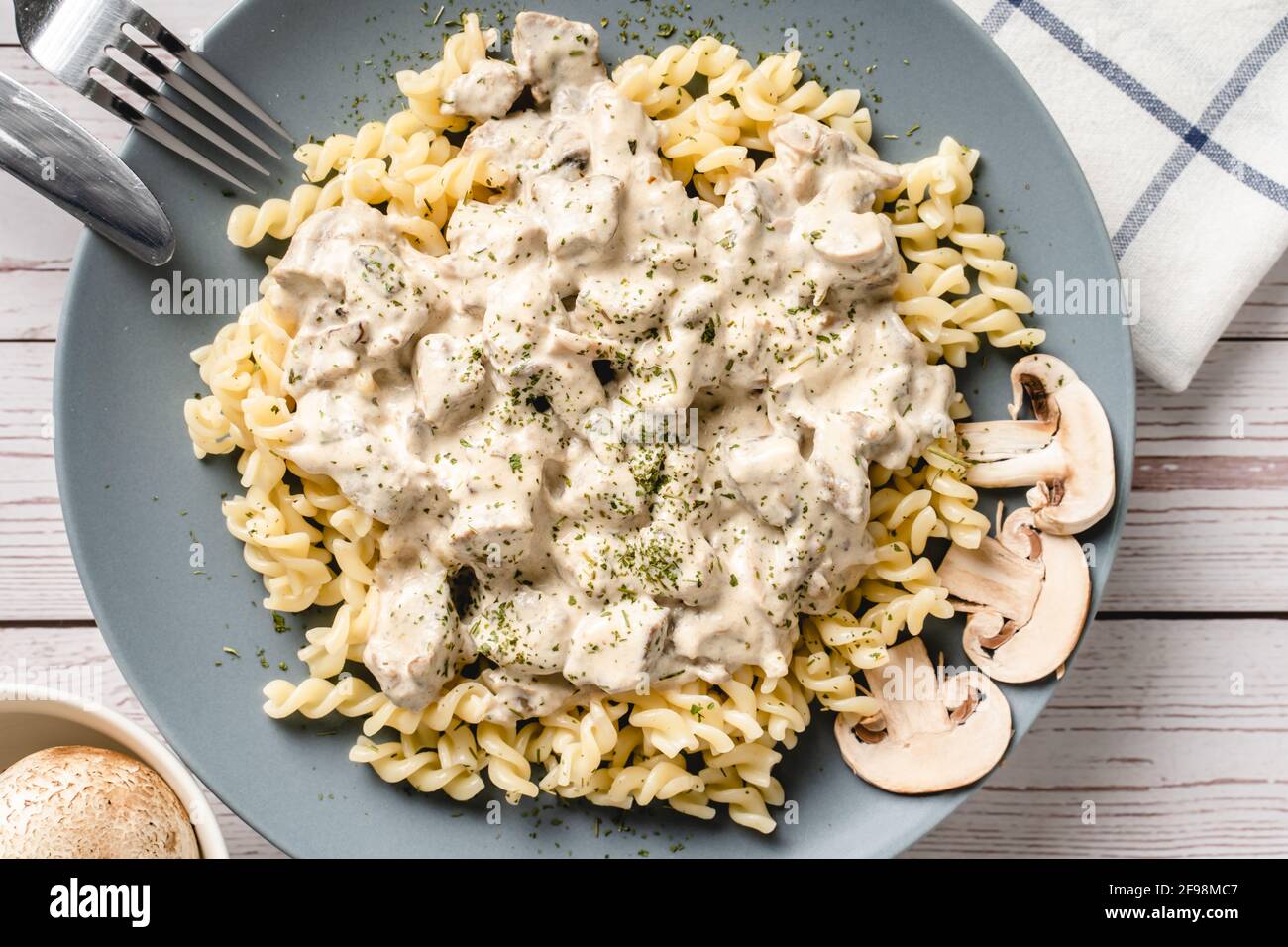 Tagliatelle con salsa cremosa ai funghi di champignon bianchi della foresta e pollo o carne di manzo - cibo fatto in casa in piatto sulla vista dall'alto del tavolo Foto Stock