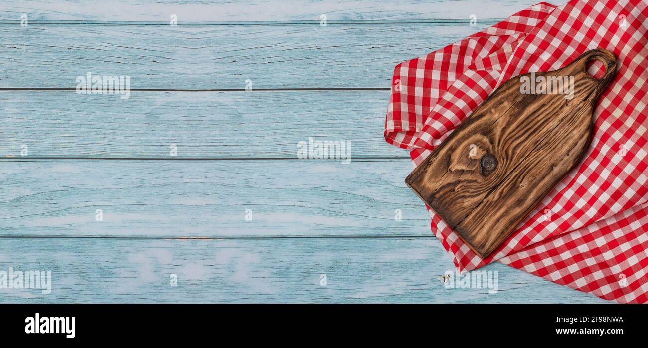 Tagliere con tovagliolo rosso a scacchi su sfondo rustico Foto Stock
